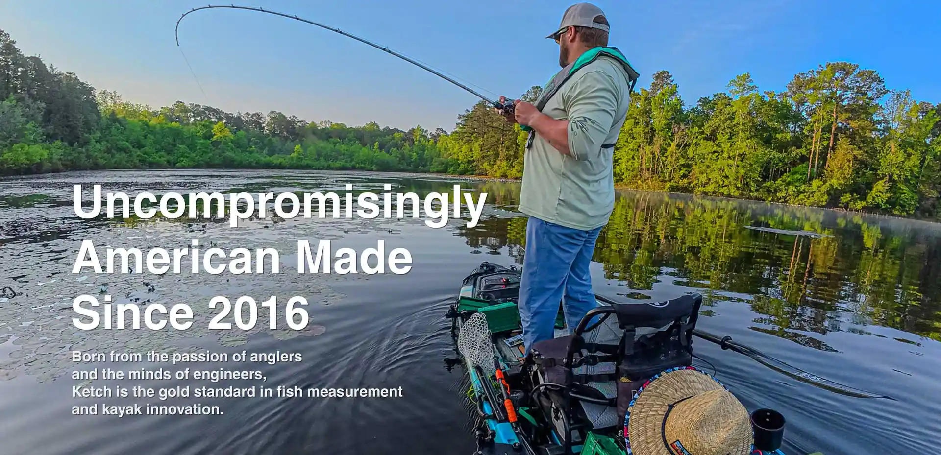 Uncompromisingly American Made Since 2016, showing a man setting the hook on a fish from his kayak in a scenic lake with matted vegetation.